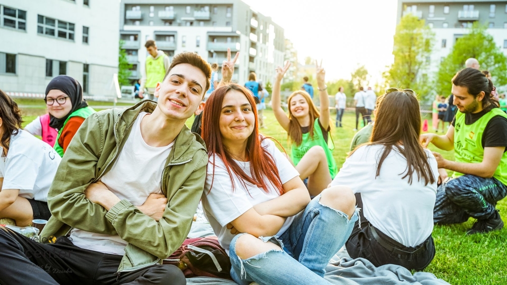 Studenci z Welcome Center siedzący na trawie na kampusie Uniwersytetu w Siedlcach.